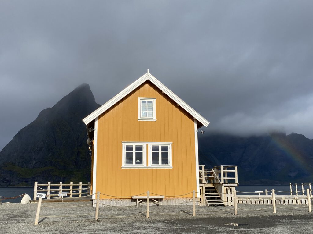 gelbes Haus in Sakrisøy mit Regenbogen
