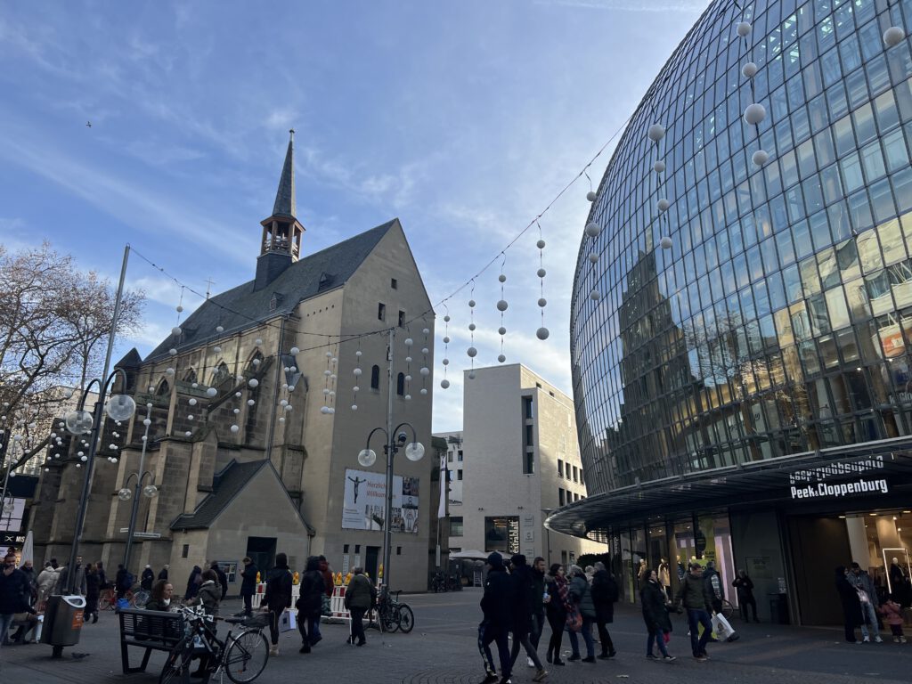 Antoniterkirche spiegelt sich in der Fassade von Peek&Cloppenburg