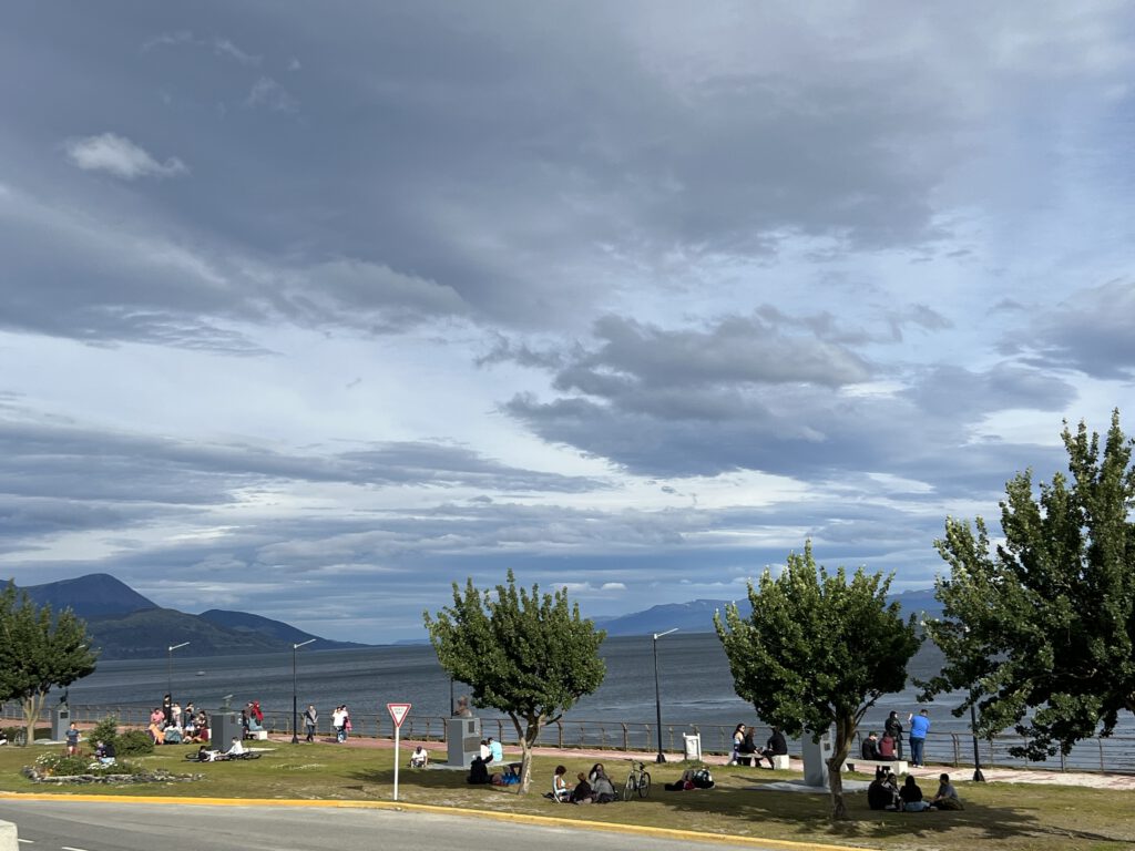 Menschen sitzen in Ushuaia in der Sonne am Wasser